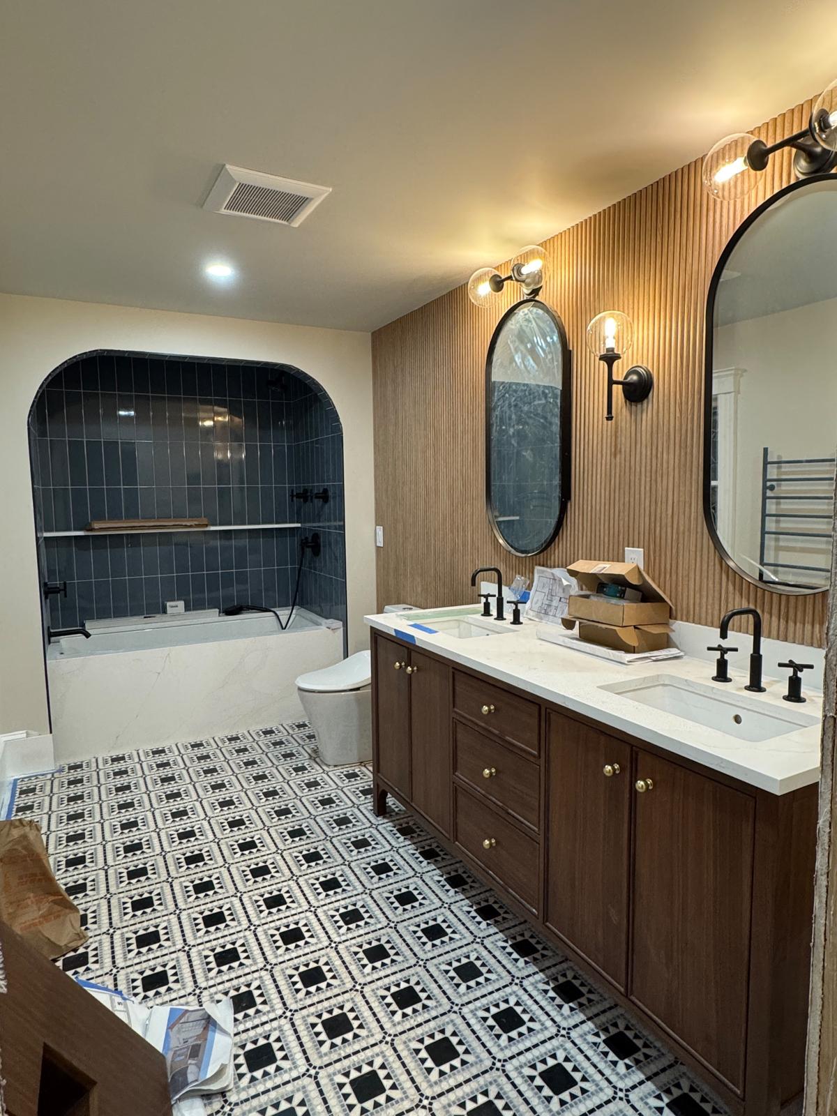 Bathroom remodel — arched bathtub alcove in blue tile, double vanity and fluted accent wall