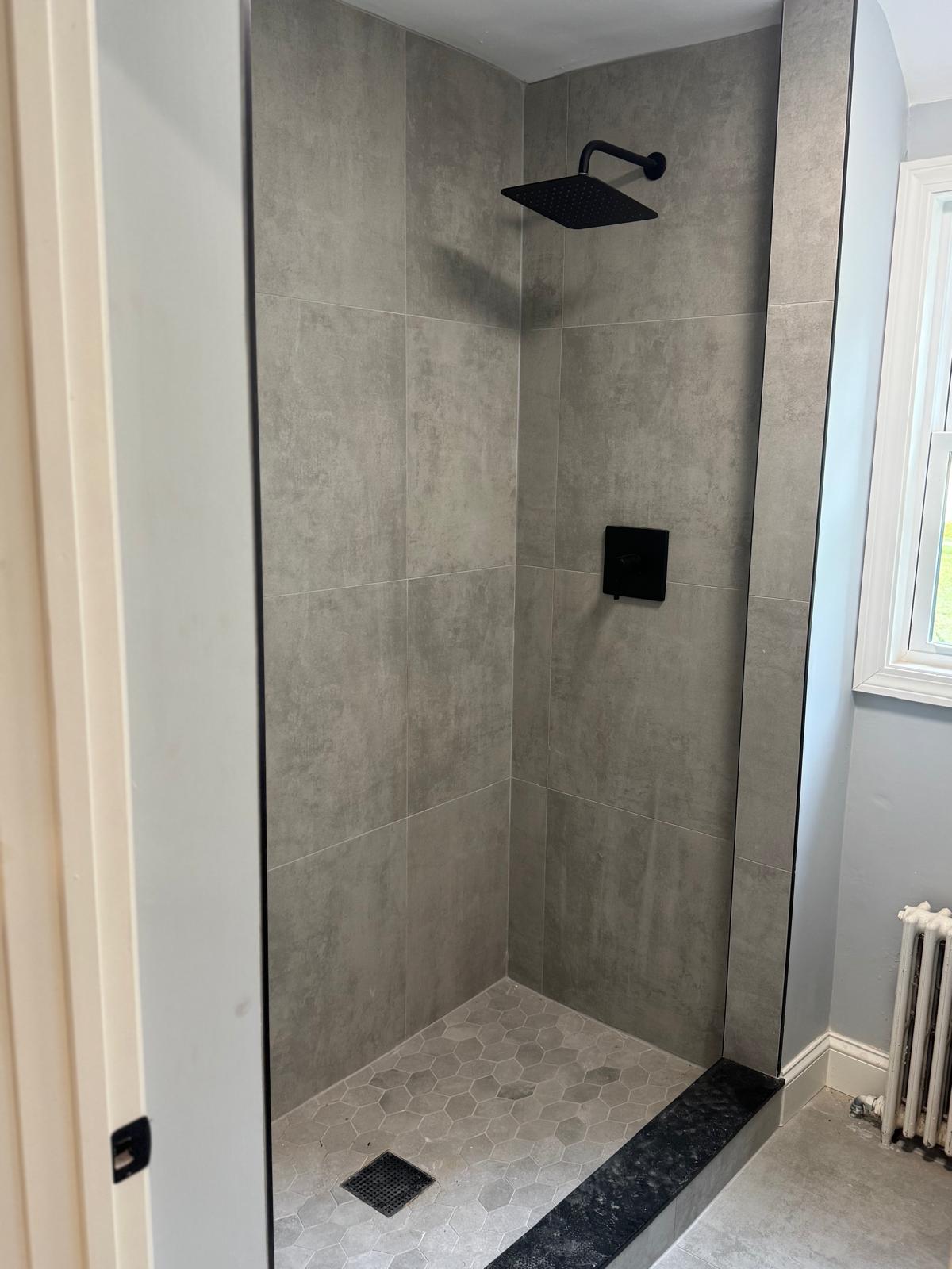 Walk-in shower — large-format concrete-look tile, hexagon floor and matte black fixtures