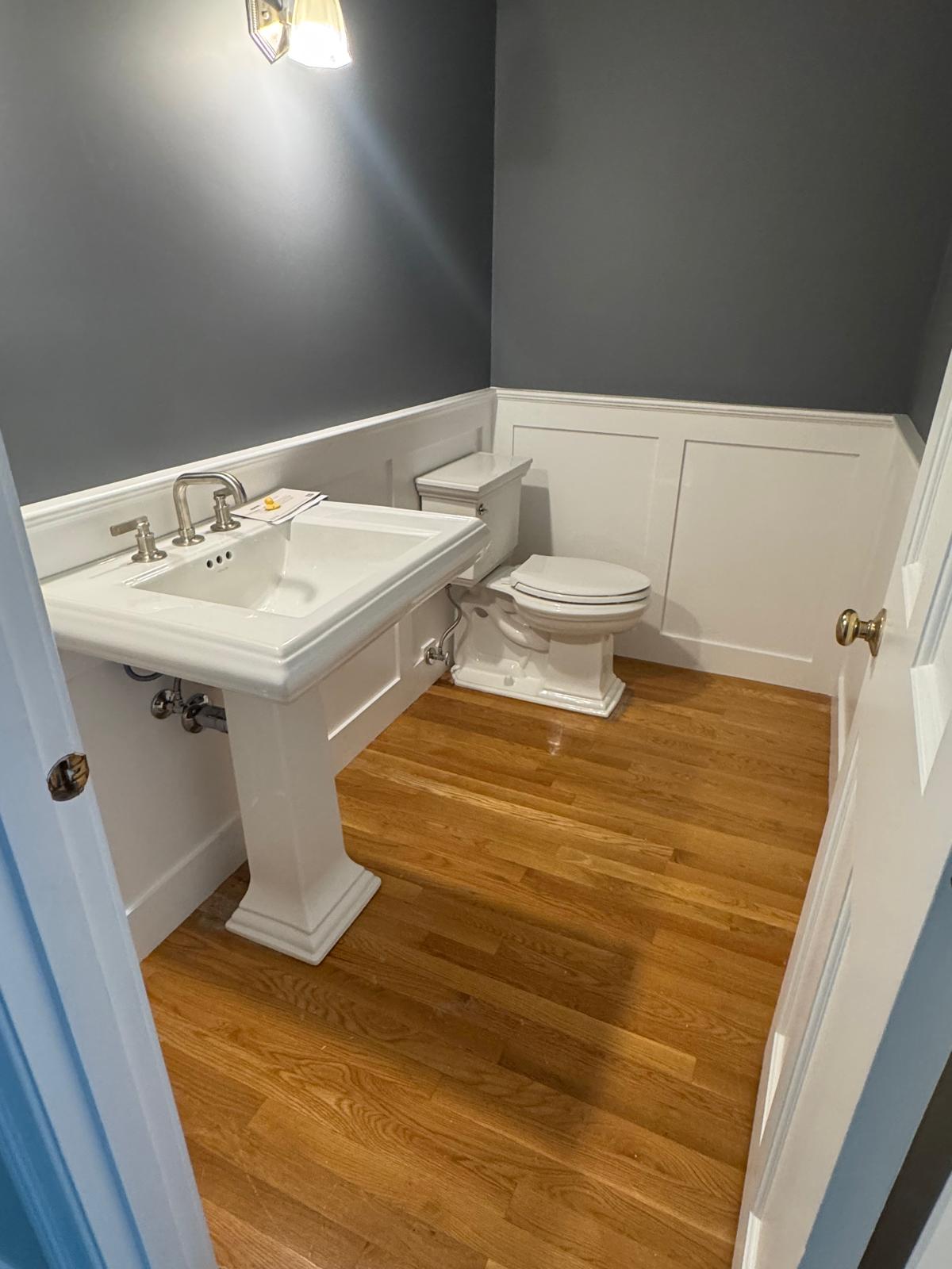 Powder room — pedestal sink, wainscoting and hardwood floors