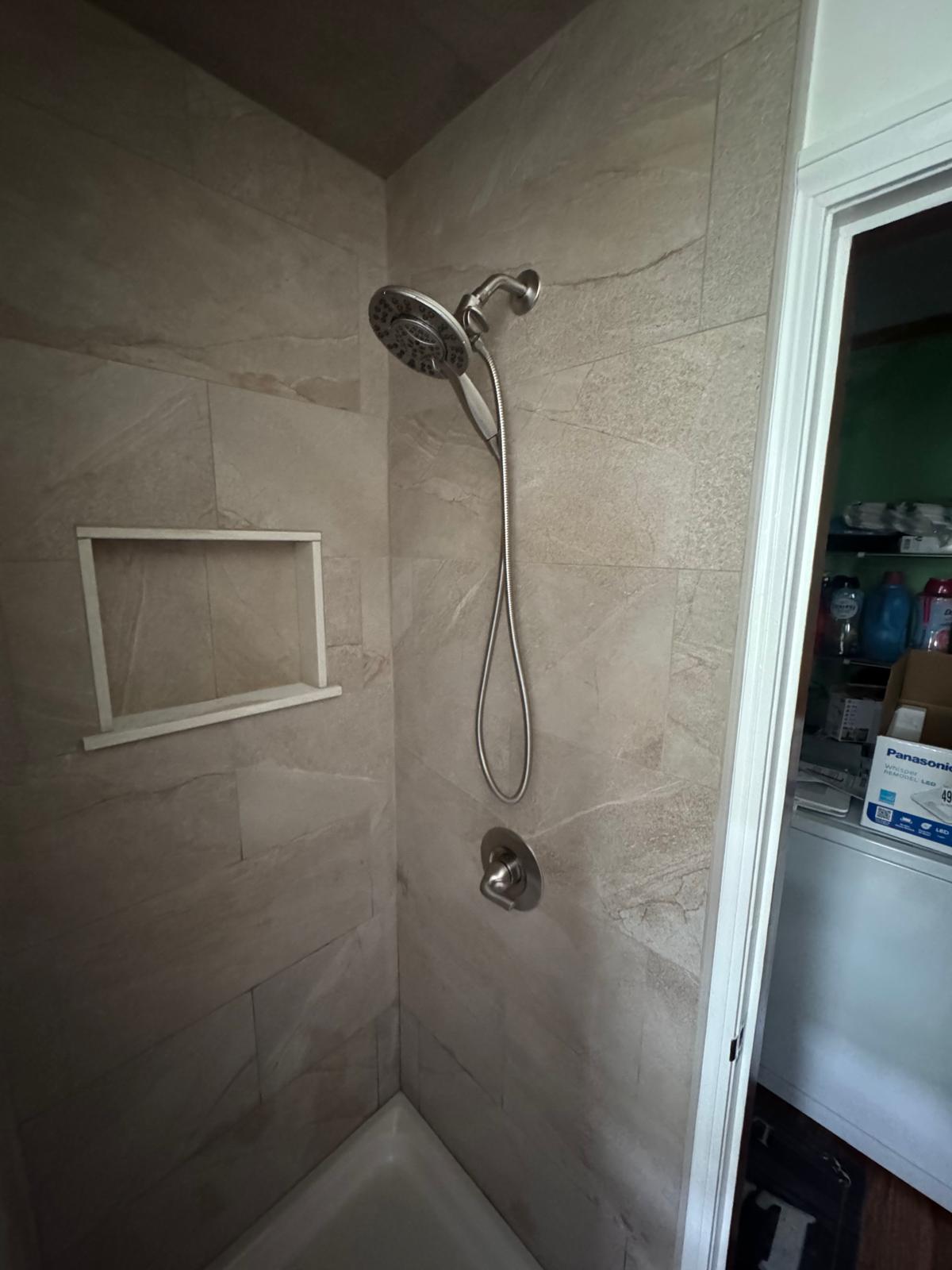 Shower stall — beige stone tile with recessed niche and brushed nickel fixtures
