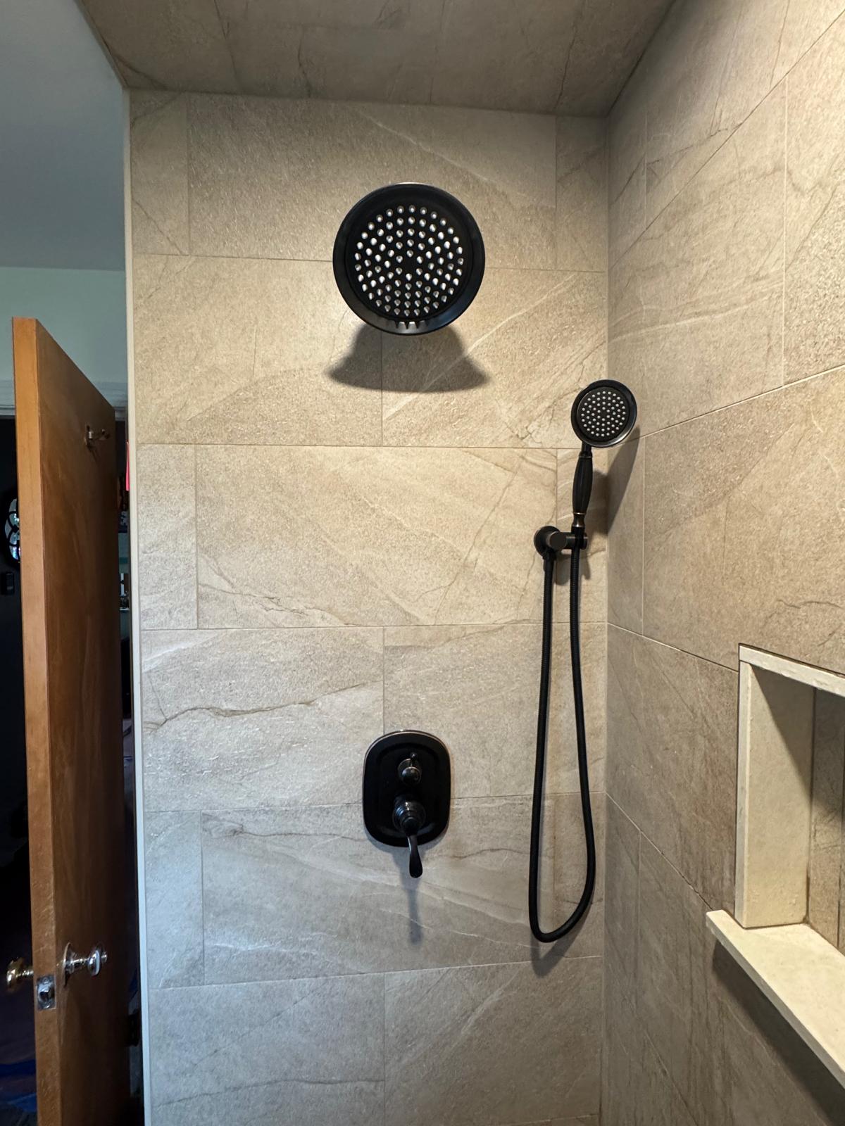 Walk-in shower — beige textured tile, recessed niche and matte black fixtures