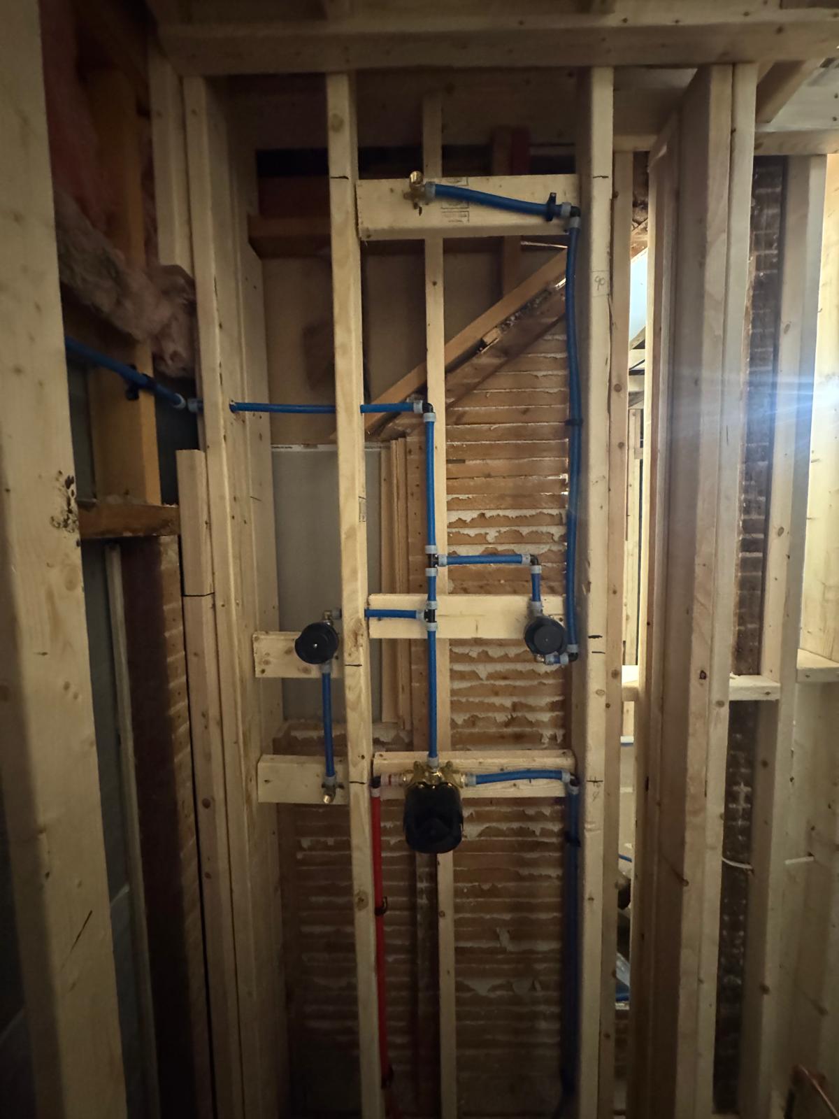 During — shower wall framing with blue PEX lines and valve boxes
